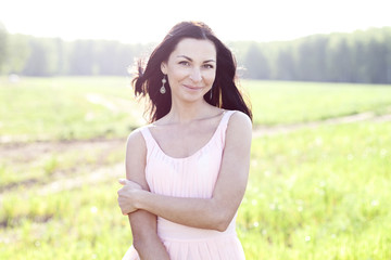 Fototapeta na wymiar Beautiful woman standing in a field pink dress, fashion style, the concept of portrait outdoor