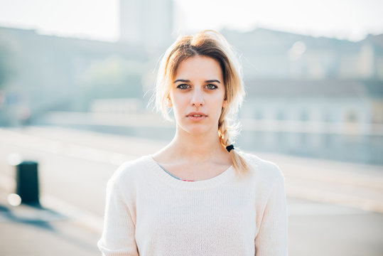 Half Length Of Young Beautiful Caucasian Blonde Woman Outdoor In City Back Light Looking In Camera, Serious - Pensive, Thinking Future, Melancholy Concept