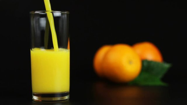 man pouring orange juice into a glass on a black background
