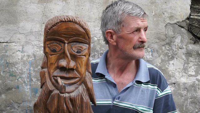 man holding a smoking mask carved from linden wood