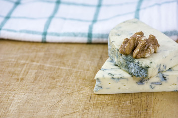 Two tasty pieces of cheese roquefort and walnut on wooden background
