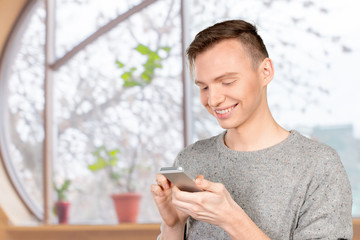 Young man typing text message on his cellphone