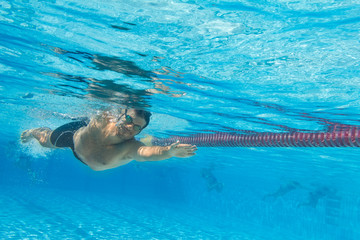 Lachender Mann schwimmt im Freibad - Unterwasseraufnahme © TeamDF