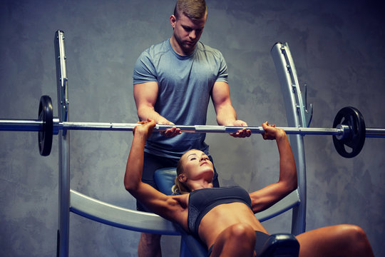 man and woman with barbell flexing muscles in gym