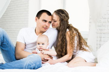 Mother and father with little baby in a bed