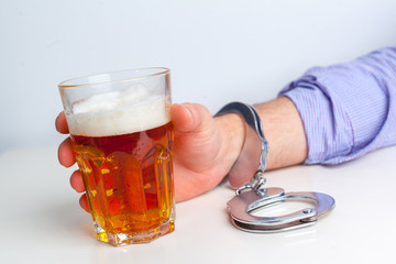 Glass of beer with handcuffs as symbol for alcohol abuse