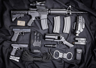 Rifle, gun, knife with sheath, compass and notebook with pen on on black cloth