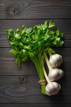 bunch of parsley and garlic on wooden background