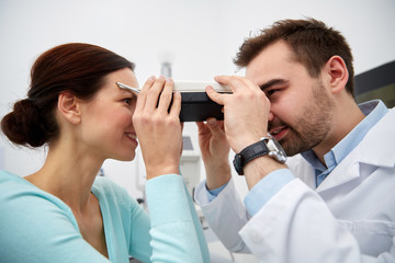 optician with pupilometer and patient at eye clinic