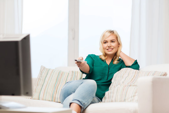 smiling woman with remote watching tv at home