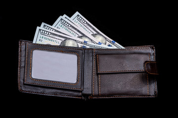 One hundred dollar bills in  dark leather purse isolated on black background