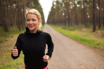 Joggerin l&auml;uft auf einem Schotterweg im Wald 