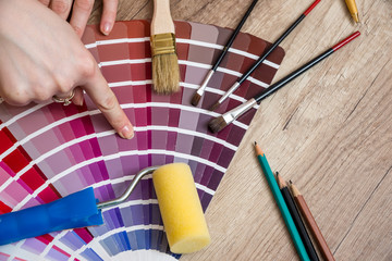 Woman hand showing to sample color chart with tools on desk