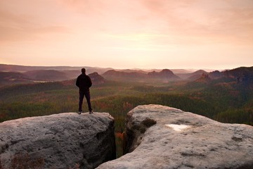 Hiker on sharp cliff in rocky empires park, watching over misty and foggy morning gulch to horizon.