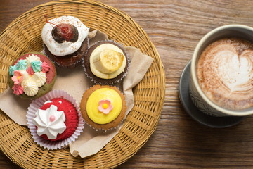 Cupcakes with hot chocolate on old wooden table.