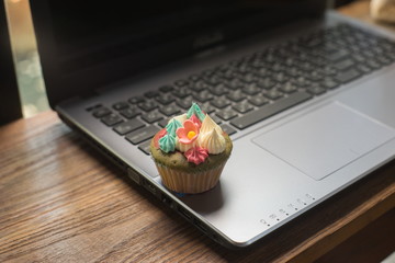 Laptop and cupcakes on wood table.