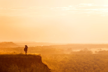 Naklejka na ściany i meble Boy with tourist on a cliff at sunset