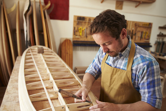 Man Building Bespoke Wooden Surfboard In Workshop - Powered by Adobe