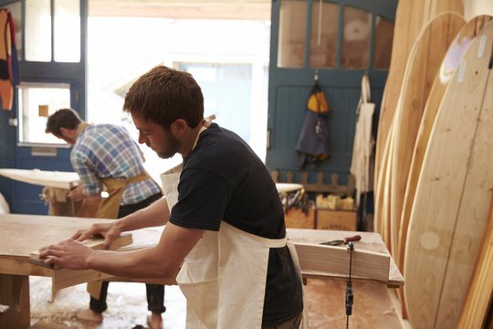 Men Building Bespoke Wooden Surfboard In Workshop