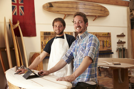 Carpenters In Surfboard Workshop Using Digital Tablet