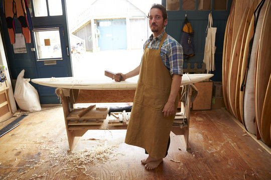 Portrait Of Carpenter Making Bespoke Surfboards In Workshop