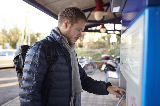 Young Man Buying Train Ticket At Railway Station
