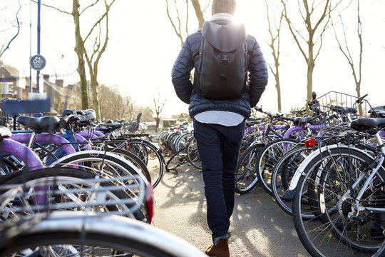 Rear view of man leaving bicycle in cycle park at railway station