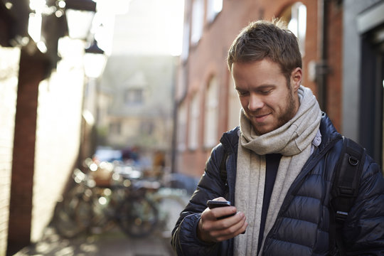 Smiling man using smartphone outdoors