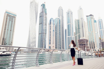 Fototapeta na wymiar Businesswoman pulling a suitcase in a big city.