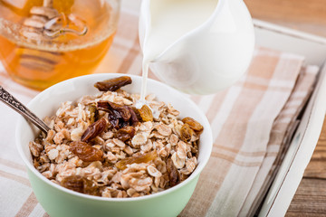 oatmeal with honey and milk for breakfast on rustic wooden table.
