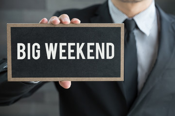 Big weekend, message on blackboard and hold by businessman