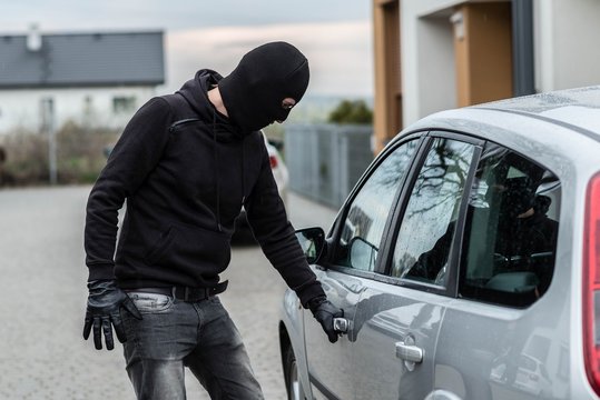 Car thief pulls the handle of a car.