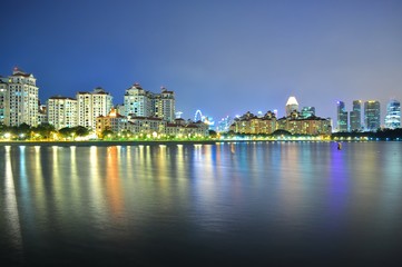Greenery by Kallang River (south of Singapore), with downtown skyline and colourful reflections in the background..