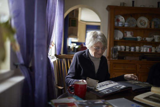 Senior Woman Looking Through Photo Album At Home