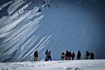 Snowboarders and skiers are on the top of the mountain before th
