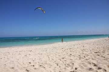 Fototapeta na wymiar A child on the beach looking at the kitesurfer