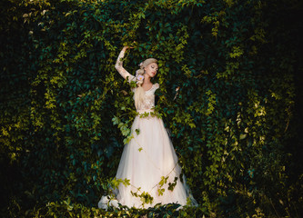Fantasy woman fashion model posing touches the green leaves of the ivy plant beautiful countess in...