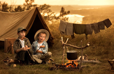 Two of children sitting around the campfire travelers