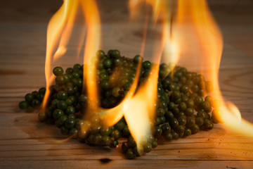 burning pile of green pepper on a wooden background