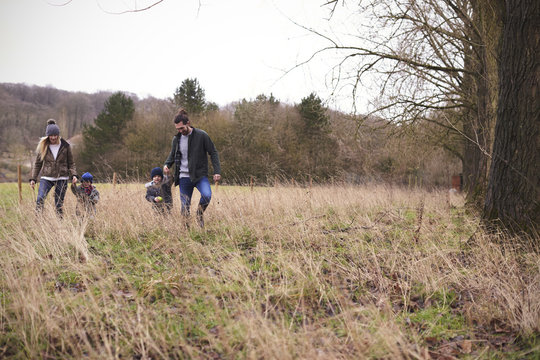 Family On Winter Walk Through Field Together