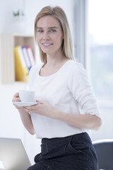 Beautiful Blond Businesswoman in Office with Coffee