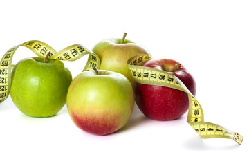 Green and red apple wrapped with a tape measure,on white background