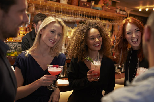 Group Of Friends Meeting For Evening Drinks In Cocktail Bar