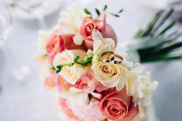 Obraz na płótnie Canvas Wedding rings on a bouquet of roses