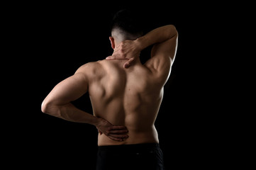 Fototapeta na wymiar back view of young man with muscular body holding his neck and low back suffering spinal pain