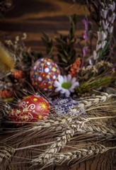 Fototapeta na wymiar Easter background. colored Easter eggs in the nest, composition of dried flowers, plants and ears of wheat. on wooden background. Easter theme. Happy Easter.