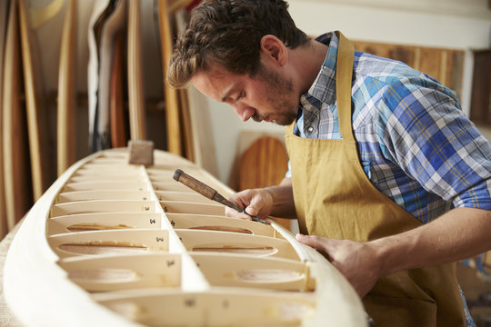 Carpenter working on surfboard in workshop