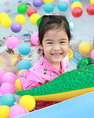 Fototapeta na wymiar Asian girl playing in a pool with colorful balls