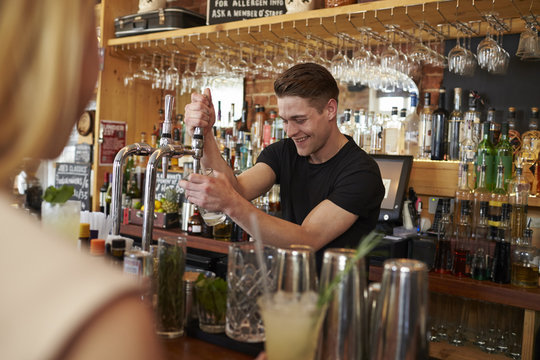 Bartender Serving Customers In Busy Bar