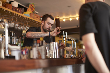 Bartender Giving Cocktail Making Lesson to Friends In Bar